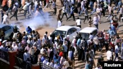 FILE - Sudanese demonstrators run from tear gas lobbed to disperse them as they march along the street during anti-government protests in Khartoum, Sudan, Dec. 25, 2018.