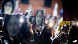 People hold pictures of slain journalist Daphne Caruana Galizia as they protest outside the office of the Maltese Prime Minister Joseph Muscat, calling for his resignation, in Valletta, Malta, Nov. 29, 2019.