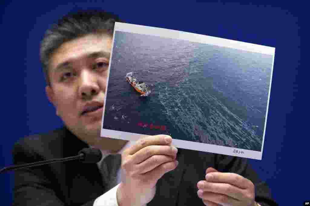 中国国家海洋局生态与环境保护司副司长霍传林在新闻发布会上展示一艘救援船和海上浮油的照片。中国官员说,他们还在争论是否打捞上个月沉没的伊朗油轮桑吉号。