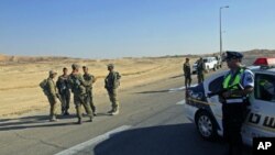 Israeli soldiers and a policeman patrol near the scene where gunmen launched several attacks, ambushing a bus and cars, north of the Red Sea resort of Eilat, August 18, 2011