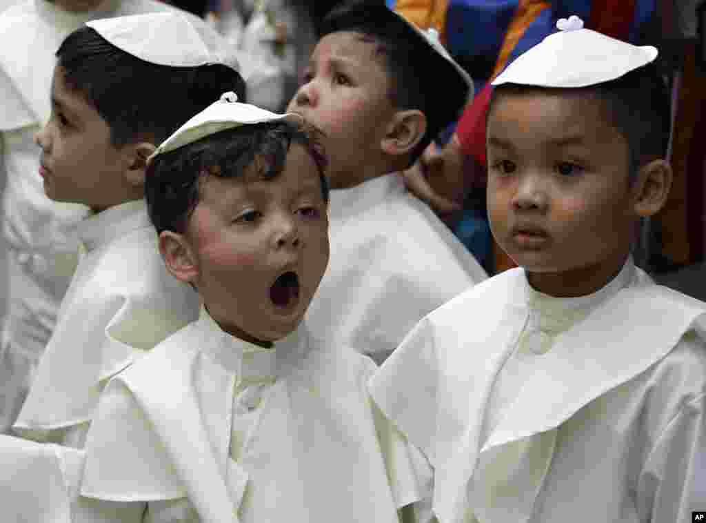 Seorang anak yang berpakaian seperti Paus menguap saat menunggu upacara kanonisasi di Vatikan terhadap Paus Yohanes Paulus II dan Paus Yohanes ke-23.