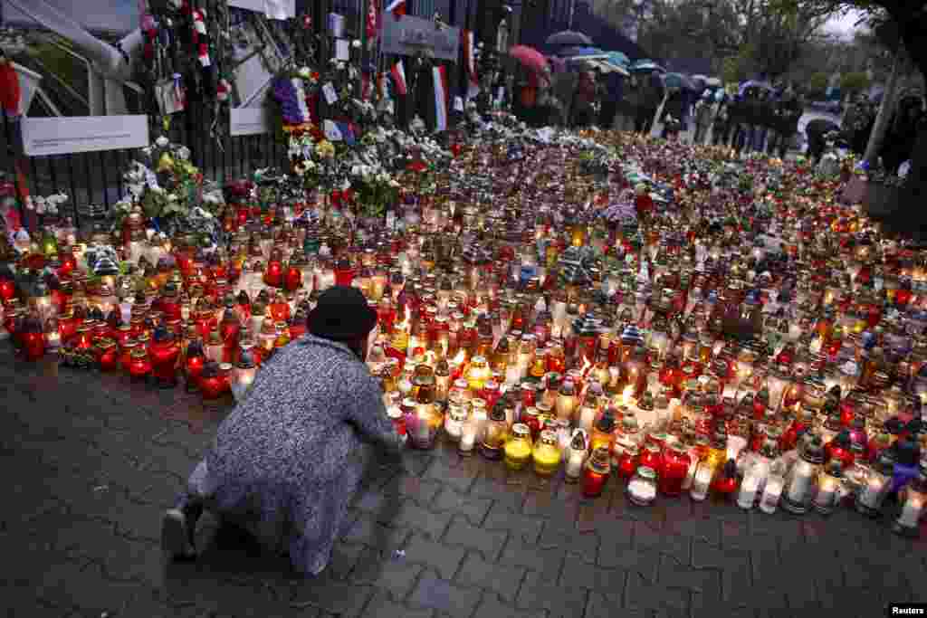 A girl lays a candle to commemorate victims of attacks in Paris in front of the French embassy in Warsaw, Poland.
