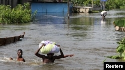 People wade through a flood with their belongings after their houses were submerged in the Amassoma community in Bayelsa state, Nigeria, October 6, 2012. 