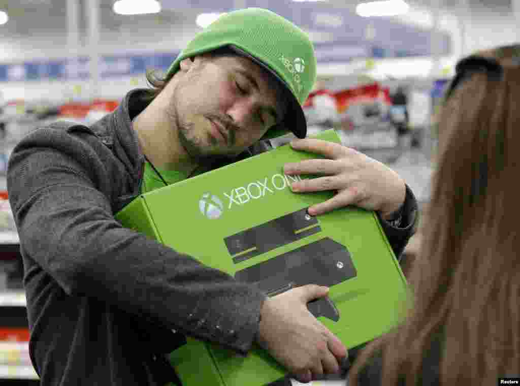 Emanuel Jumatate, dari Chicago, memeluk Xbox One baru miliknya yang baru dibelinya di Evanston, Illinois. Microsoft mengklaim Xbox One sebagai sistem hiburan menyeluruh dan bukan hanya untuk game.