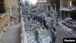 People inspect the damage at a site after it was hit by shelling carried out by rebels at Syrian government-held areas of Aleppo, Syria, in this handout picture provided by SANA, July 11, 2016.