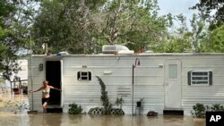 Una mujer sale de una casa móvil en un área no incorporada en el este del condado de Harris, cerca de Houston, el sábado 4 de mayo de 2024 por la tarde. Intensas lluvias han provocado fuertes inundaciones en la región.