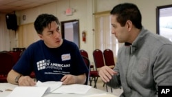 Iván Parra (izquierda), de Florida Immigrant Coalition, ayuda a Eduardo Feitosa, de 33 años, originario de Brasil, a presentar sus documentos para solicitar la ciudadanía estadounidense.