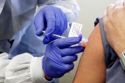 FILE - A volunteer receives a shot in the first-stage safety study clinical trial of a potential vaccine for COVID-19, at the Kaiser Permanente Washington Health Research Institute in Seattle, March 16, 2020.