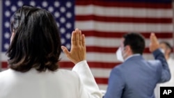 FILE- People take the oath of citizenship during a naturalization ceremony at the U.S. Citizenship and Immigration Service's Field Office in New York City, July 2, 2020.