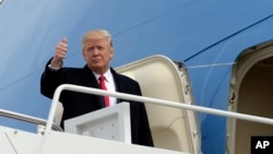 លោក​ប្រធានាធិបតី​ Donald Trump ធ្វើ​សញ្ញា​ឲ្យមេដៃ​ពីលើជណ្តើរ​នៃយន្តហោះ​ទ័ពអាកាស​នៅ​មូលដ្ឋាន​កងទ័ព​អាកាស​ Andrews នៅ​រដ្ឋ​ Maryland (រូបថត​ថ្ងៃទី១៧​ ខែកុម្ភៈ​ ឆ្នាំ២០១៧​)។ 