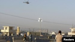 Petugas keamanan Afghanistan melakukan penjagaan ketat, saat helikopter NATO melintasi lokasi kejadian ledakan bom bunuh diri di Jalalabad (2/12).