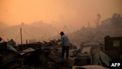 A man stands amid the remains of a burnt house after a forest fire devastated Santa Olga, 240 kilometres south of Santiago, Jan. 26, 2017.