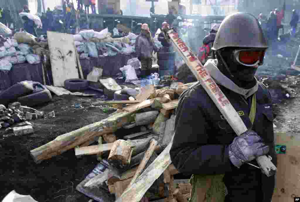 A protester guards the barricade in front of riot police in Kyiv, Ukraine.
