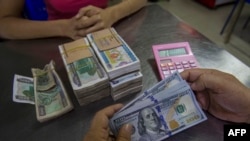 In this photograph taken on December 16, 2016 a money changer handles a transaction of US dollar and Myanmar Kyats as the local currency weakens. - The Myanmar Central Bank reference rate stands 1,365 Kyats to the US dollar as of December 16, 2016. (Photo