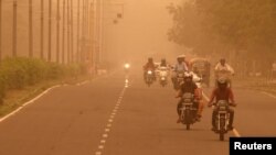 FILE - Commuters make their way amidst haze and dust in Chandigarh, India, June 15, 2018.