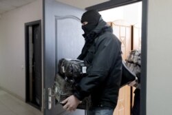 A policeman leaves the BAJ office after a raid in Minsk, on Feb. 16, 2021. Police in Belarus also raided the homes and offices of 25 journalists, rights defenders and trade union members.