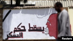 A member of the Muslim Brotherhood and supporter of ousted Egyptian President Mohamed Mursi walks in front of graffiti that reads "Down with the military rules" at the Rabaa Adawiya Square, where they are camping, in Nasr city area, east of Cairo Jul. 28,