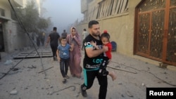 Warga Palestina tampak meninggalkan area kamp pengungsi Maghazi di pusat Jalur Gaza saat serangan udara Israel menghantam lokasi tersebut pada 6 November 2023. (Foto: Reuters/Yasser Qudih)