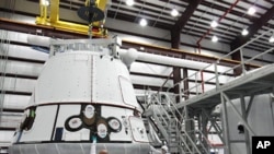 The SpaceX Dragon capsule is lifted to be placed atop its cargo ring inside a processing hangar at Cape Canaveral Air Force Station in Florida.