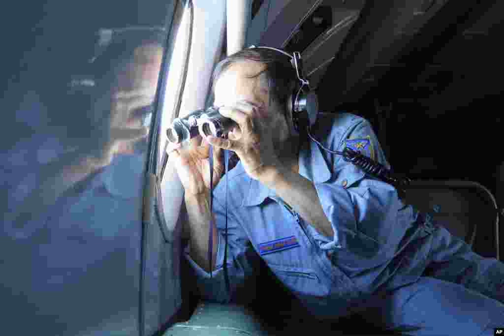 Kolonel Angkatan Udara Vietnam menggunakan teropong di atas pesawat dalam misi pencarian Malaysia Airlines penerbangan MH370 yang hilang di Teluk Thailand, 13 Maret 2014.