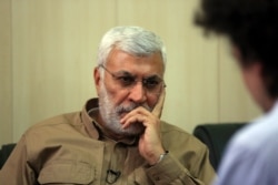 FILE - Abu Mahdi al-Muhandis, a commander in the Popular Mobilization Forces, listens to a question during an interview outside Fallujah, Iraq, May 29, 2016.