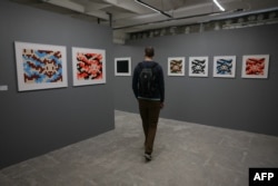 FILE - A man visits the "Space Invader Station" exhibition of street artist Invader in Paris, on February 27, 2024. (Photo by Thomas SAMSON / AFP) /
