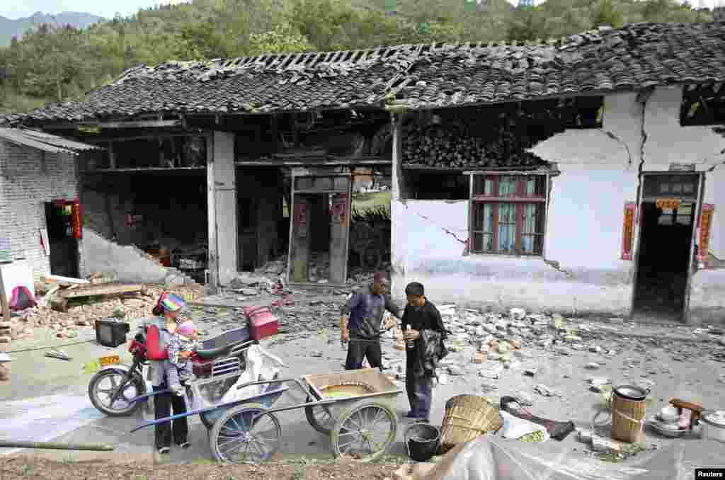 Warga berdiri di luar rumah yang hancur setelah gempa berkekuatan 6.6 mengguncang desa Longmen, wilayah Lushan, Ya'an, propinsi Sichuan, 20 April 2013.