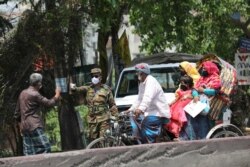 FILE - A member of the military stops people riding on a rickshaw at a check post during a government-imposed countrywide shutdown amid concerns over the coronavirus disease outbreak in Narayanganj, Bangladesh, April 9, 2020.