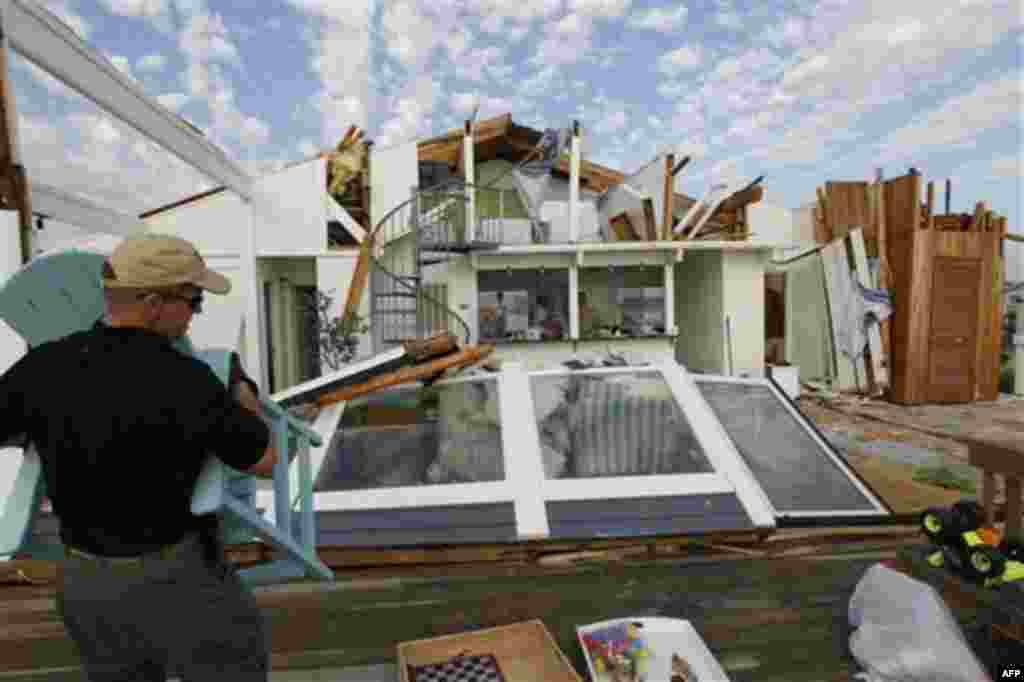 Pat Valent helps friends clear out belongings from their severely storm-damaged beach home in the Sandbridge area of Virginia Beach, Va., after Hurricane Irene hit the region, Sunday, Aug. 28, 2011. Irene inflicted scattered damage over such a broad area