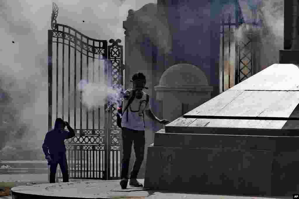 A protester fires a flare during clashes with security forces outside of Cairo University in Giza, March 26, 2014.