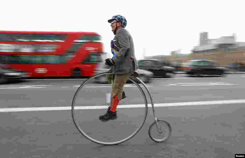 Seorang peserta acara 'Tweed Run', berpakaian tradisional Inggris dan mengendarai sepeda unik, melewati jembatan Westminster di London, Inggris.