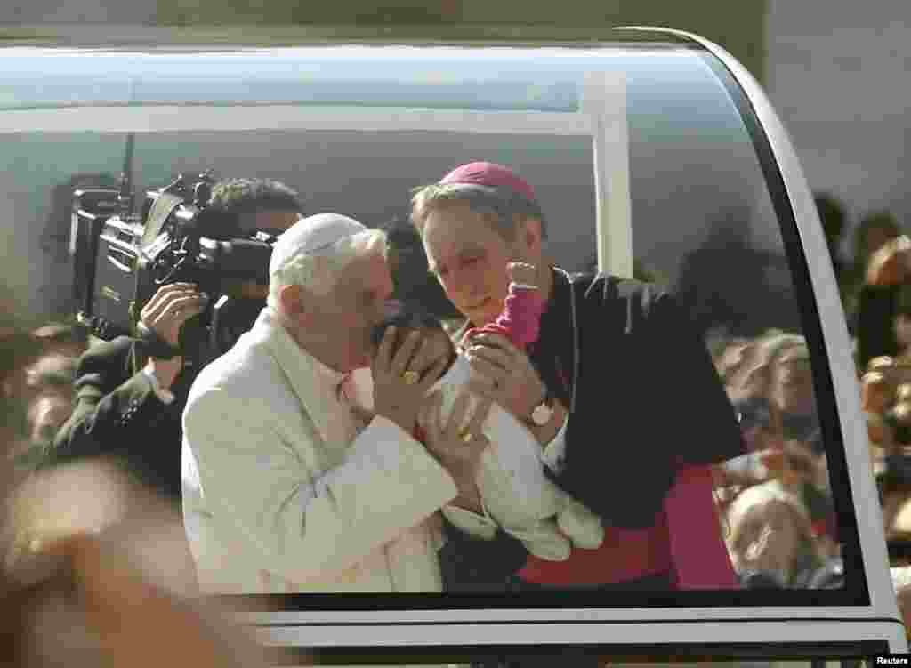 Pope Benedict blesses a baby as he rides around St. Peter's Square to hold his last general audience at the Vatican Feb. 27, 2013.