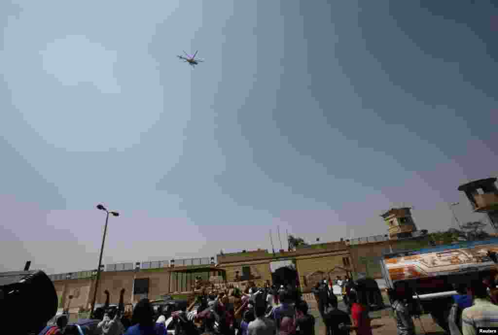 Para pendukung presiden terguling Hosni Mubarak menyaksikan helikopter yang membawa mantan presiden itu meninggalkan penjara Tora di Kairo, 22 Agustus 2013. 