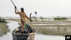 John Gafabusa, guardião do local sagrado natural de Mutyona, no Uganda, aponta para um local sagrado coberto de água no Lago Albert, a 3 de agosto de 2023. A TotalEnergies não está a proteger a santidade de centenas de sepulturas num projeto controverso, aponta relatório.
