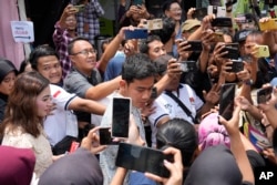 Calon wakil presiden yang juga putra sulung Presiden Joko Widodo Gibran Rakabuming Raka, tengah, berbincang dengan pendukungnya usai mencoblos di TPS Solo, 14 Februari 2024. (Foto: AP)