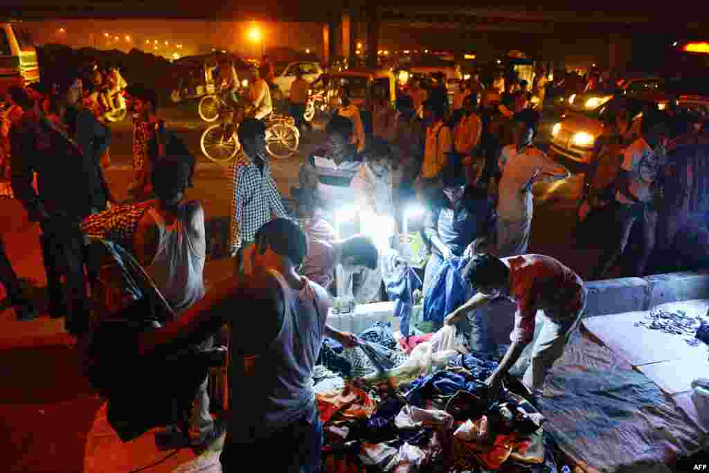 Seorang laki-laki India melihat tumpukan kemeja baru yang dijual di sebuah persimpangan yang ramai di timur New Delhi pada malam Diwali, salah satu hari raya yang paling penting dalam kalendar umat Hindu di India.