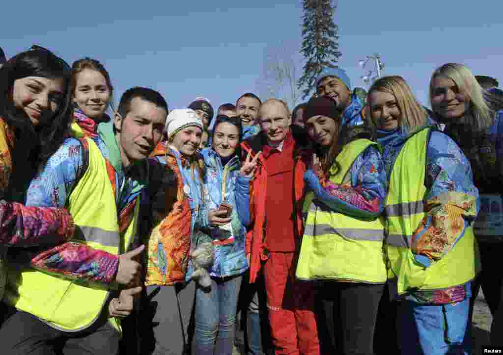 Presiden Rusia Vladimir Putin berpose dengan para sukarelawan saat mengunjungi partai estafet ski cross-country putra di Pusat Ski Cross-Country dan Biathlon Laura di Krasnaya Polyana, Rusia, 16 Februari 2014.