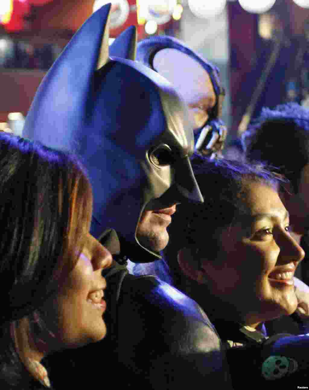 Un hombre vestido de Batman posa con los fanáticos del personaje.
