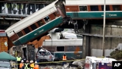 Beberapa gerbong dari kereta Amtrak jatuh ke jalan raya yang sibuk kota DuPont, Washington, Senin (18/12). 