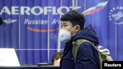资料照：一名戴着口罩的旅客在俄罗斯谢列梅捷沃国际机场的俄罗斯航空公司订票柜台旁。（2020年2月4日）