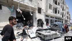 FILE - Syrians gather at a site of car bomb in the northwestern Syrian city of Idlib, Aug. 2, 2018. U.N. reports an upsurge in aerial and ground-based bombardment by Syrian and Russian forces over the past week has killed scores of civilians and displaced more than 30,000 women, children and men within the region.