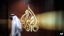 Seorang berjalan di depan logo jaringan TV Al Jazeera di Doha, Qatar. Al Jazeera telah membeli hak penyiaran pertama musim Liga Champions. 