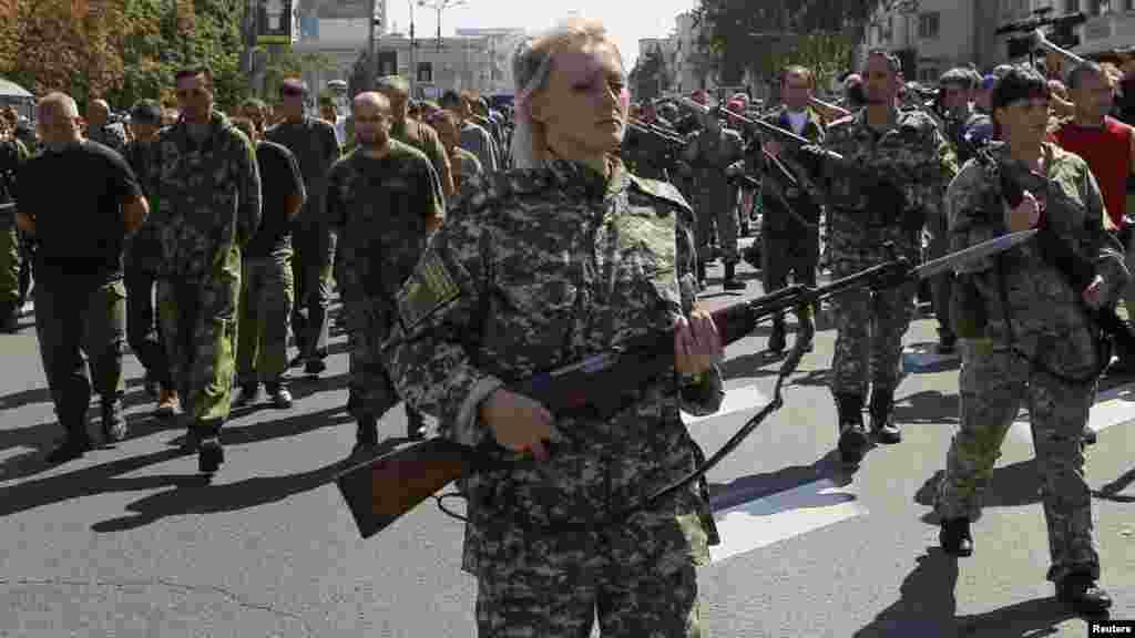 Armed pro-Russian separatists escort a column of Ukrainian prisoners of war, left, as they walk across central Donetsk, Ukraine, Aug. 24, 2014.