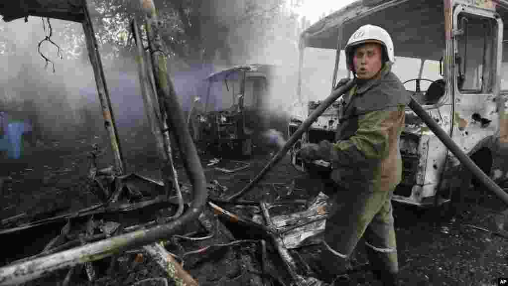 Ukrainian fire fighters put out the fire at the destroyed buses after shelling in Donetsk, eastern Ukraine, Aug. 10, 2014.