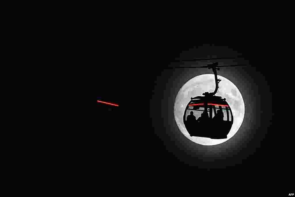 Bulan purnama "supermoon" terlihat di belakang kereta gantung di London, Inggris.