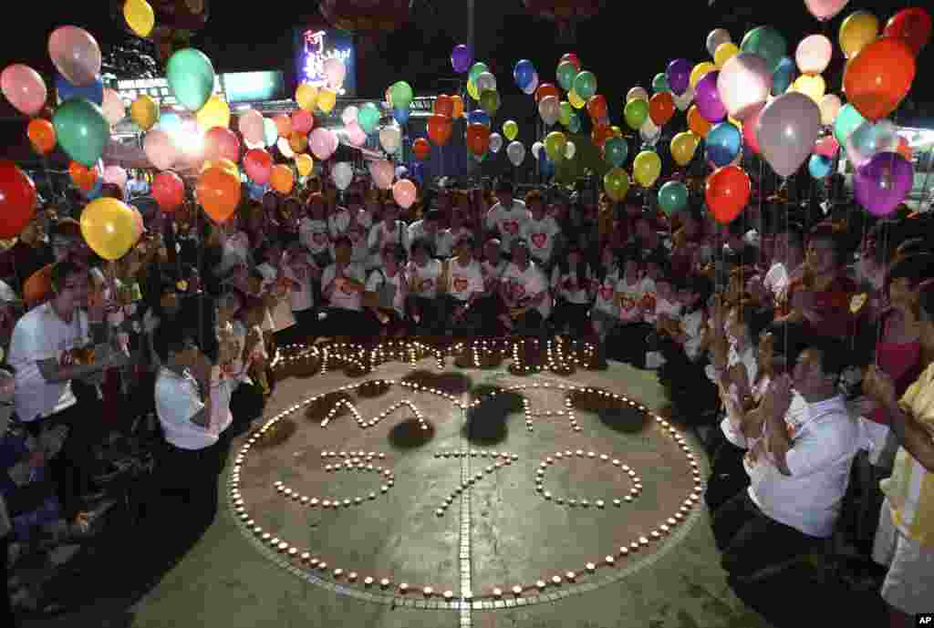 Orang-orang memegang balon dekat pesan yang bertuliskan "Doa untuk MH370" (17/3). (AP/Lai Seng Sin) 
