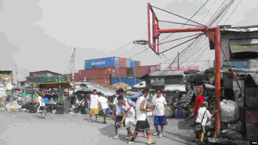 A pickup game complete with uniforms, referees and announcers at the Smokey Mountain dump site basketball court, surrounded by piles of trash bags, Manila Bay, Philippines, Dec. 12, 2013. (Simone Orendain for VOA)