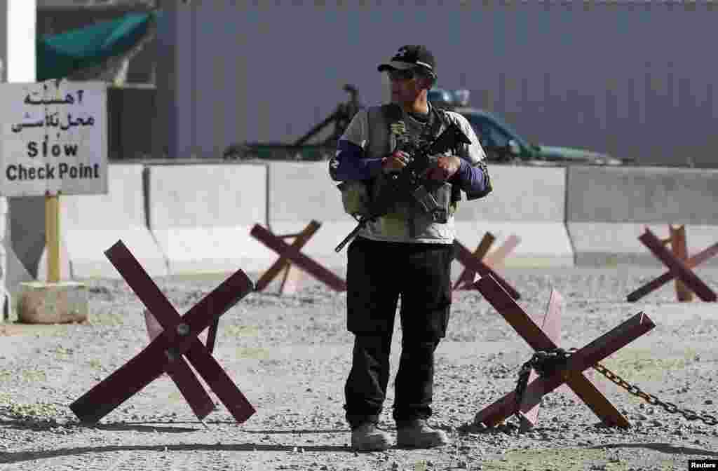 A foreign security contractor keeps watch at the site of a suicide attack, outside the counter-narcotics office near the Kabul International Airport, July 22, 2014. 