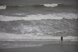 Dark clouds and high surf produced by Tropical Storm Isaias can be seen as a man continues to fish on the beach in North Myrtle Beach, S.C., Aug. 3, 2020.