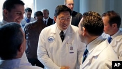Dr. Dicken Ko, direktur program urologi Rumah Sakit Umum Massachusetts, berjabat tangan dengan anggota tim operasi usai konferensi pers di Boston mengenai transplantasi penis pertama di AS (16/5). (AP/Elise Amendola)